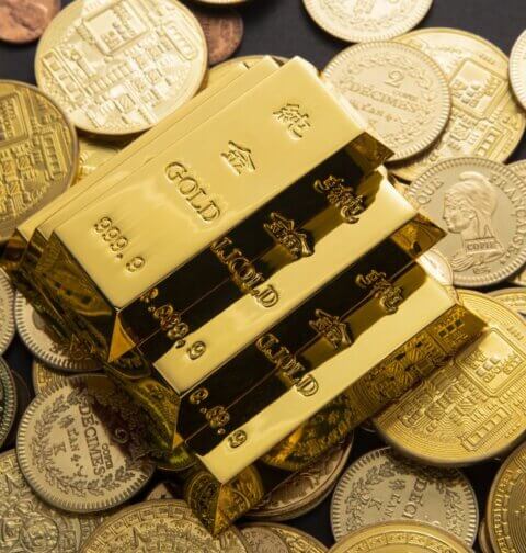 Goldbarren auf Münzen, die eine Gold-Steueroase und den verborgenen Vermögensvorteil von steuerfreiem Gold illustrieren